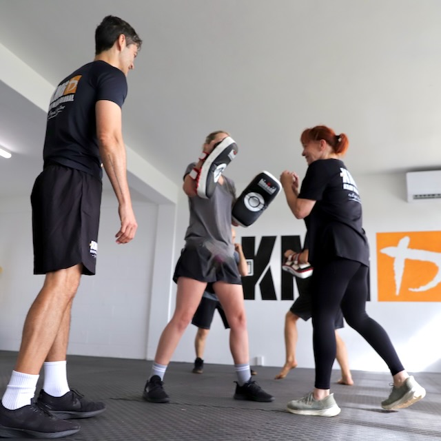 Instructor Brad coaching a woman through a Krav Maga technique at Krav Maga Auckland, Birkenhead