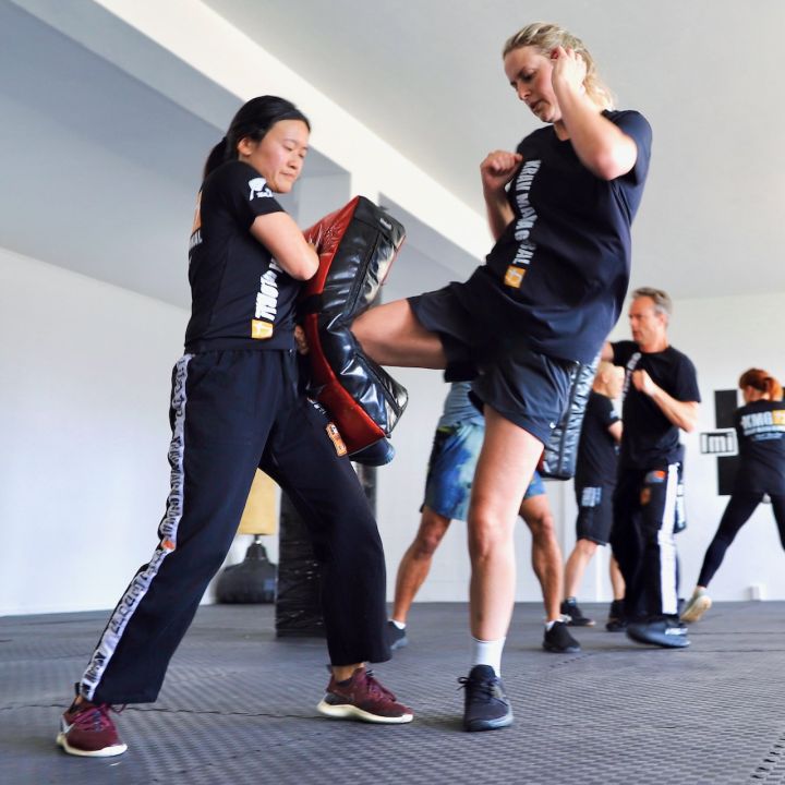Krav Maga instructor guiding a beginner through a close-range self defence drill in Birkenhead Auckland.