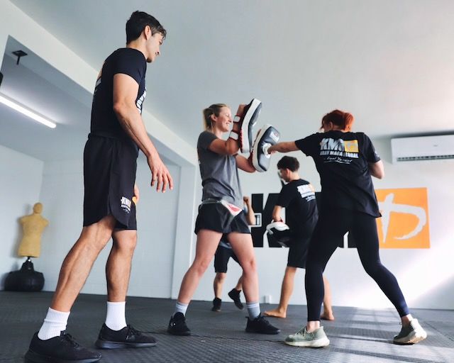 Certified Krav Maga instructor coaching beginners during a group training class