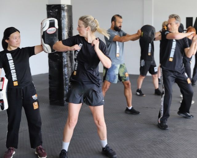 Students practising elbow strikes on pads during a Krav Maga Auckland class
